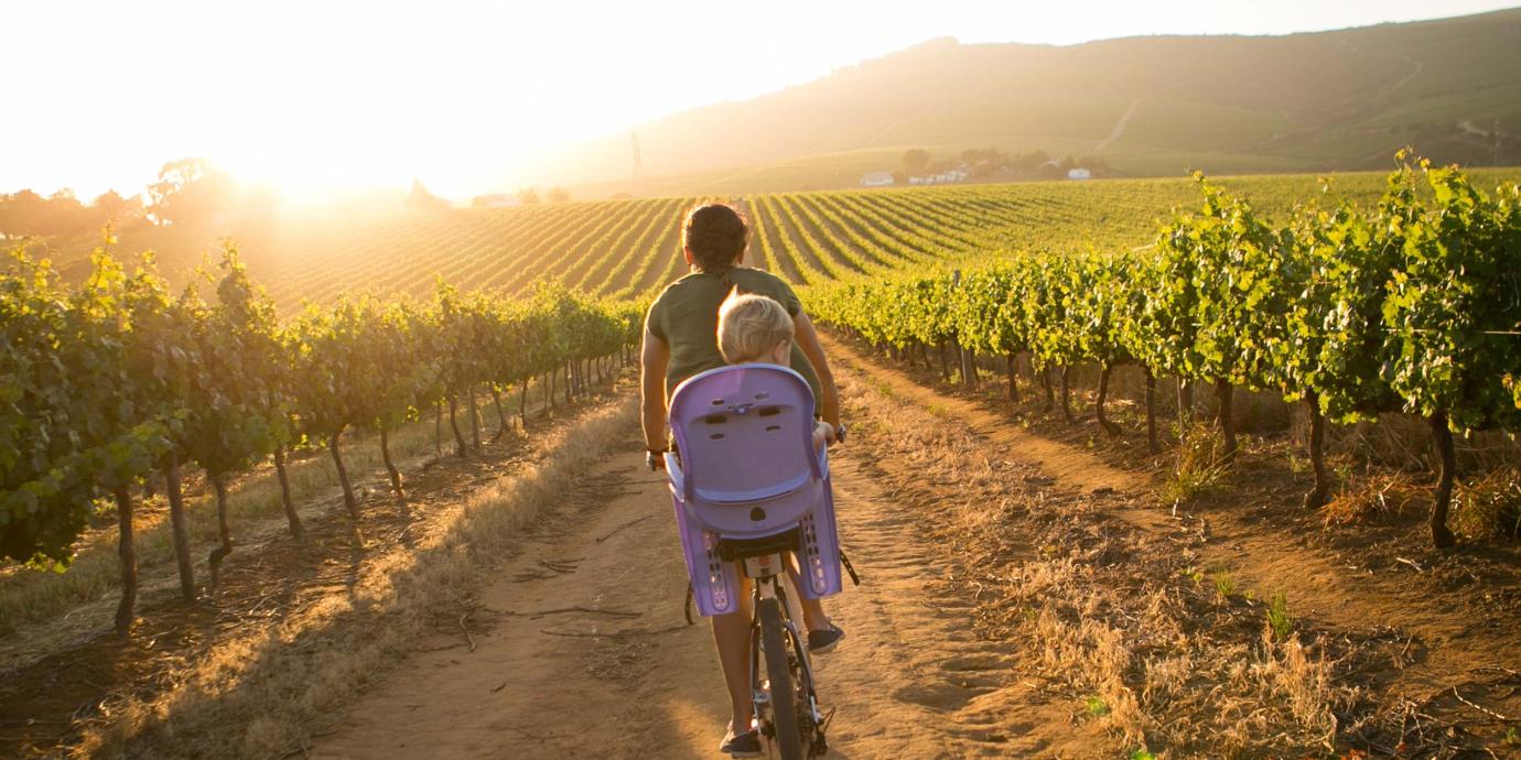 Woman and her child riding a bike in a field.